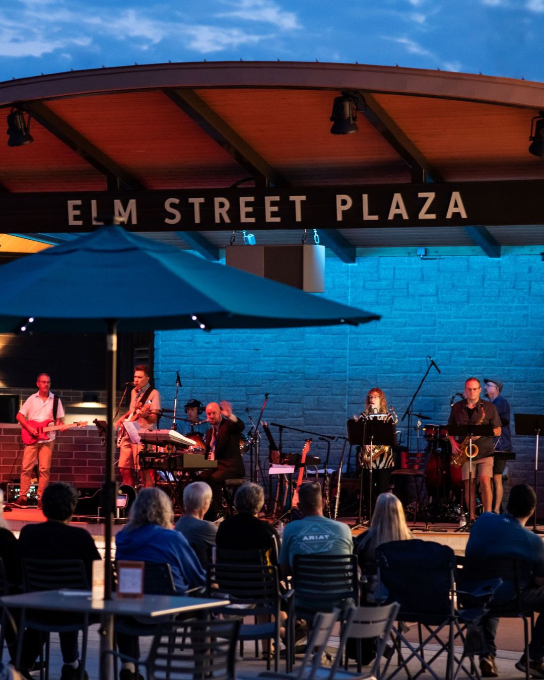 Band performing on stage at Elm Street Plaza at twilight