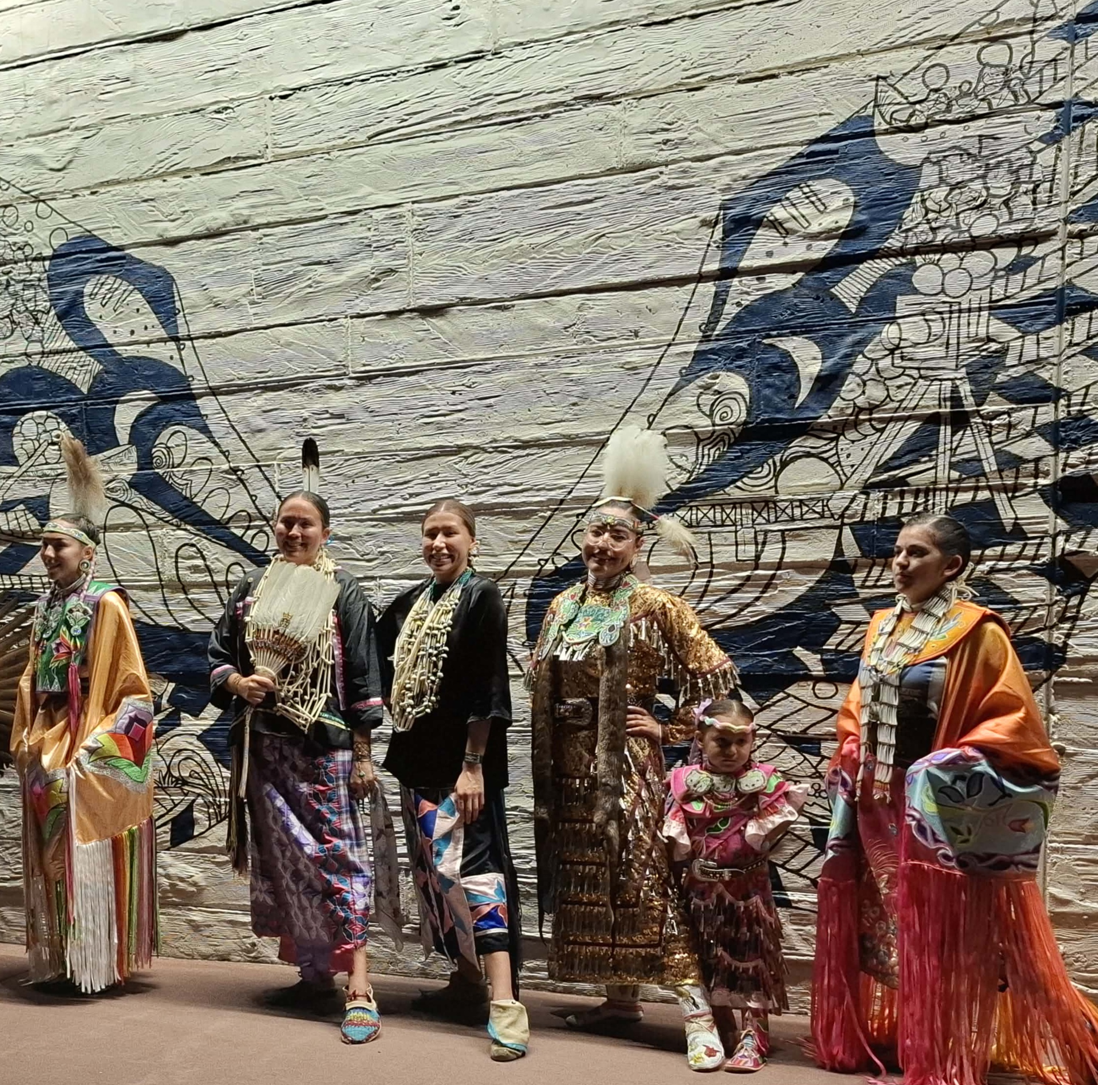 Little Priest Singers in colorful traditional regalia at the plaza mural