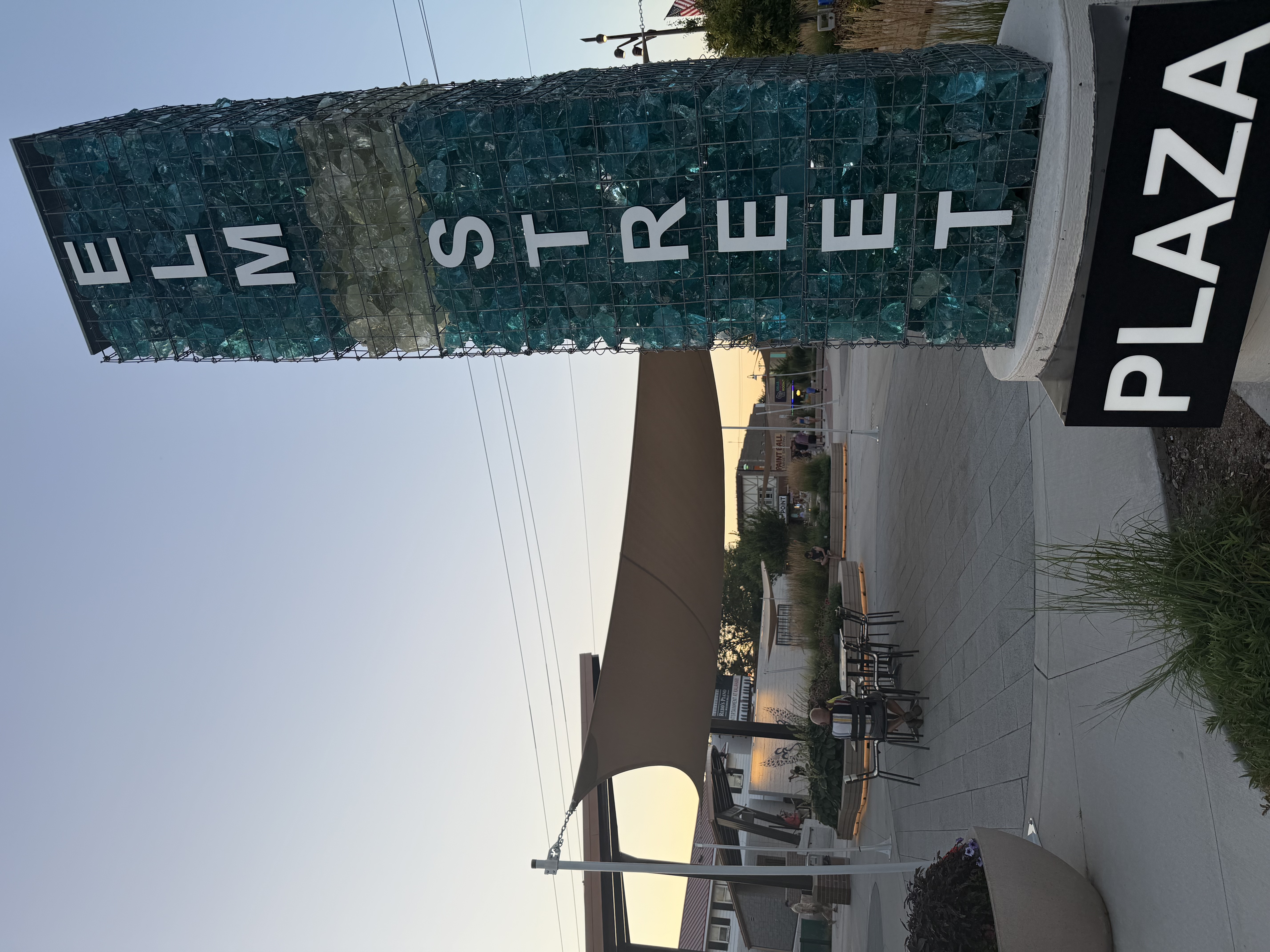Elm Street Plaza entrance sign and seating area at sunset