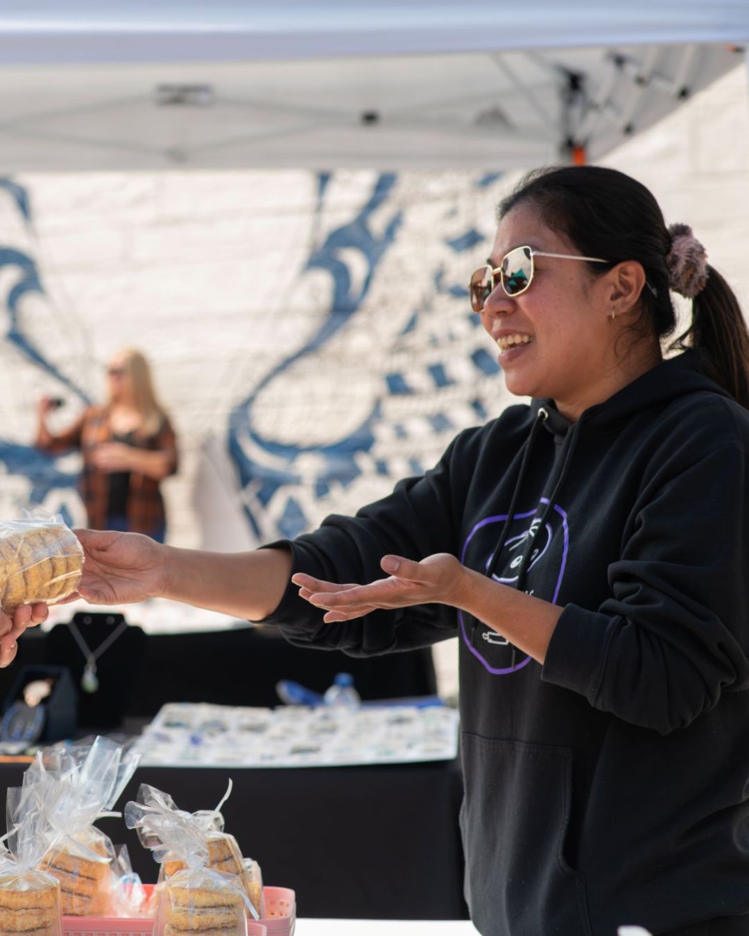 Vendor handing fresh baked goods to a customer at the market